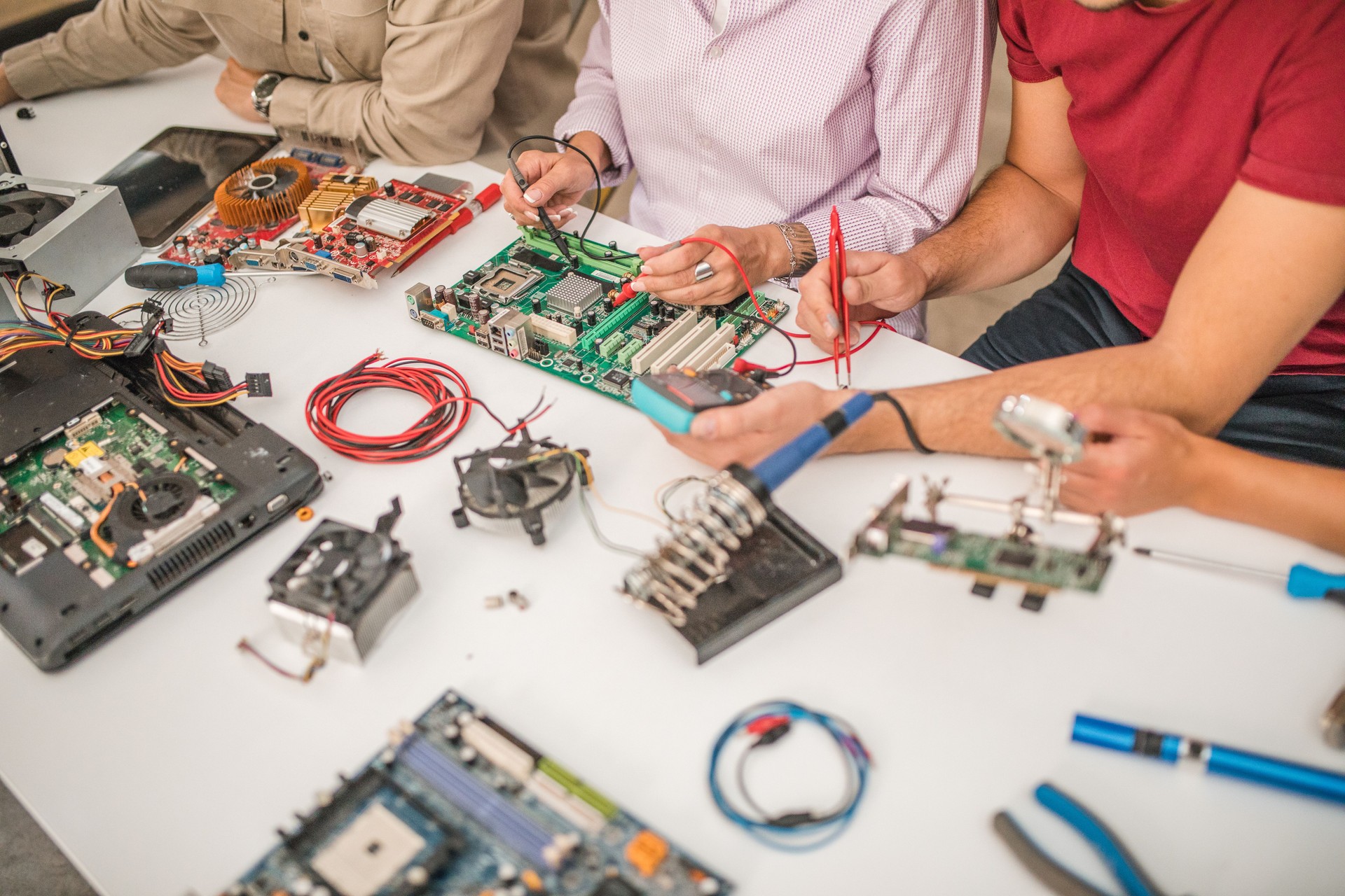 An unrecognizable female teacher shows students how a multimeter works in an electronics class